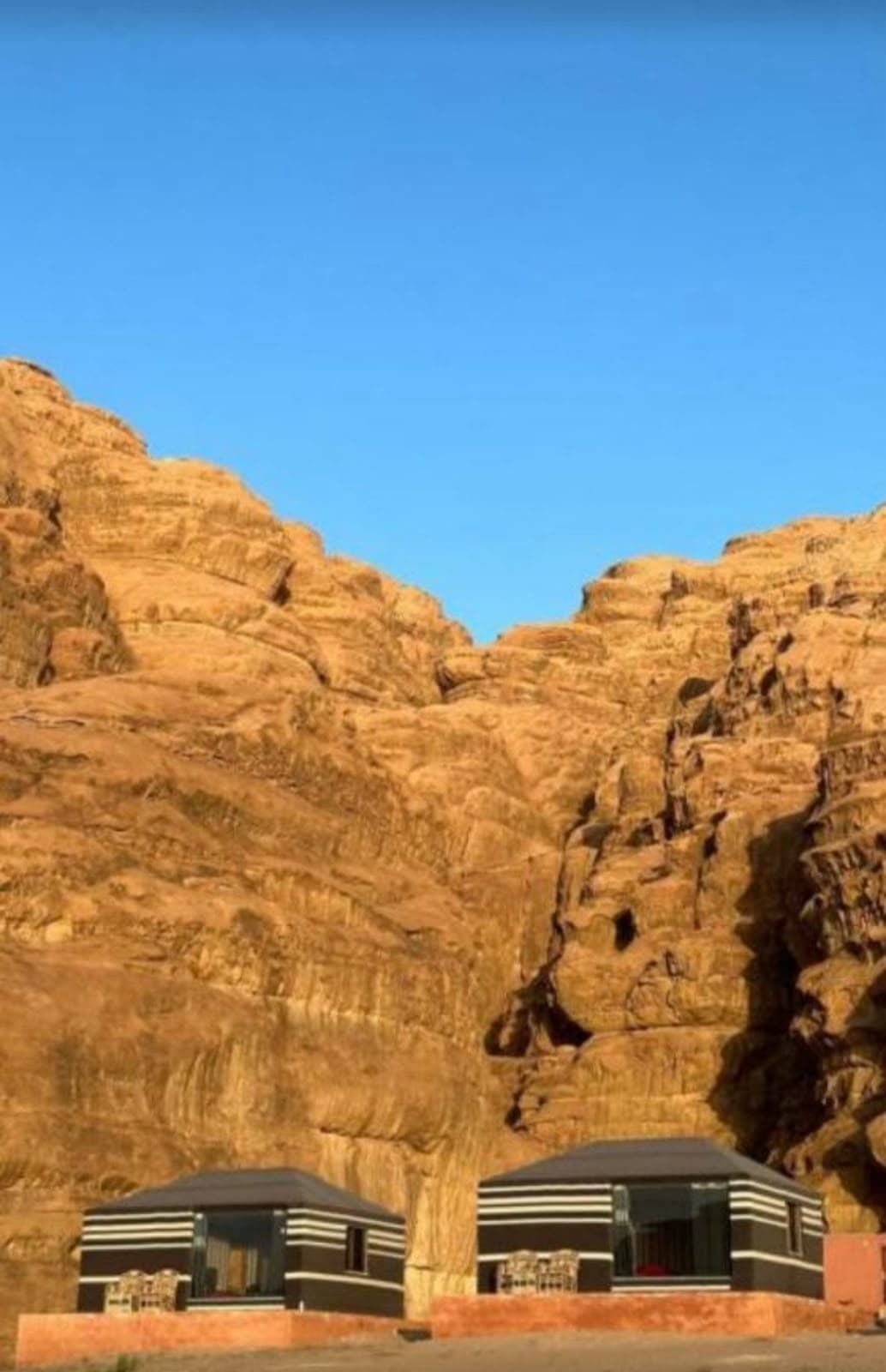 Bedouin tents nestled peacefully at the base of towering sandstone mountains