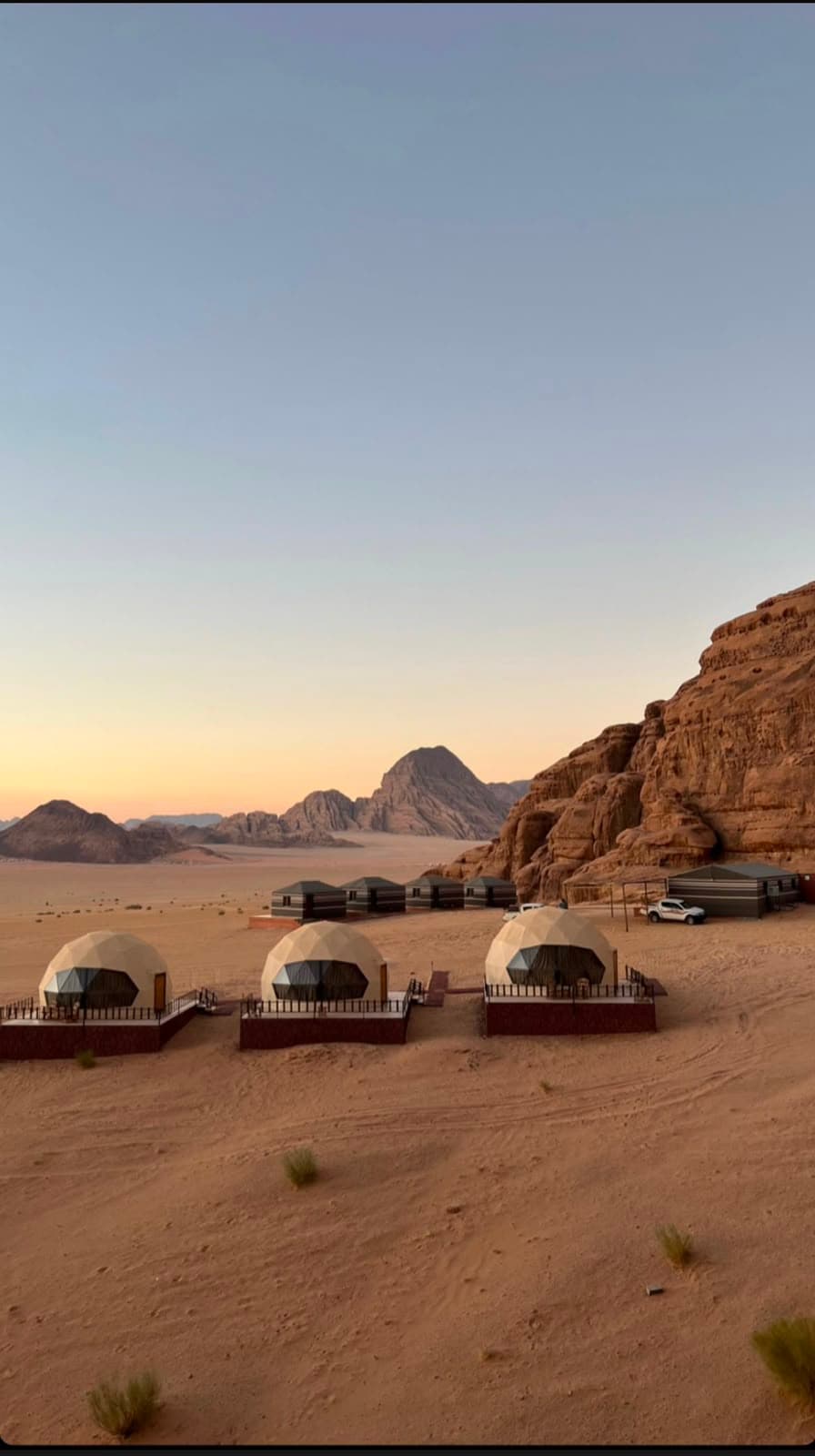 Panoramic sunset view of Mars Camp in Wadi Rum red desert sand nestled beneath majestic sandstone mountains